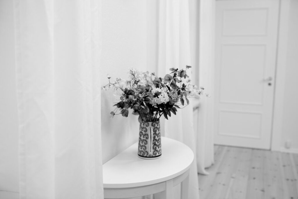 Blomster i vase på et hvidt bord i en rengjort bolig efter dødsbo